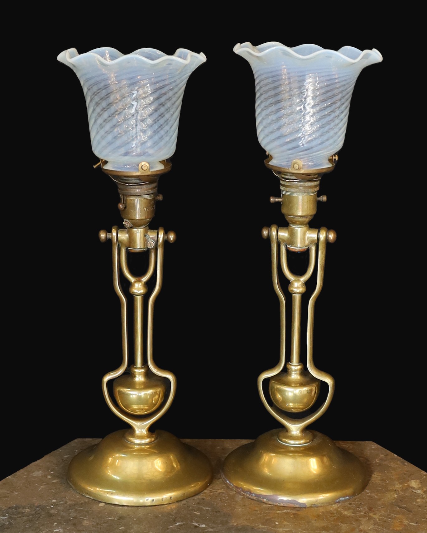 A pair of brass Pullman lamps with gimbal stems and Vaseline glass shades, modelled for wall mounting or freestanding, height to top of shade 40cm
